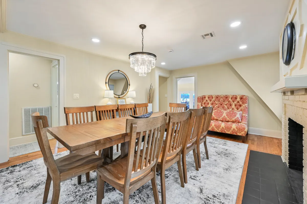 A warm, inviting dining space with a grand chandelier, colorful armchair, and a cozy fireplace. The room hints at the home's storied past, providing a glimpse of shared meals and gatherings that might have taken place here for generations.