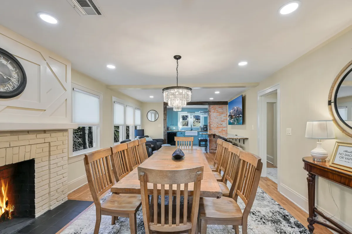 A large dining table set under a sparkling chandelier with a fireplace nearby and elegant wall decor. The scene is warm and welcoming, ideal for hosting celebratory meals or intimate gatherings, and showcases both heritage details and modern touches.